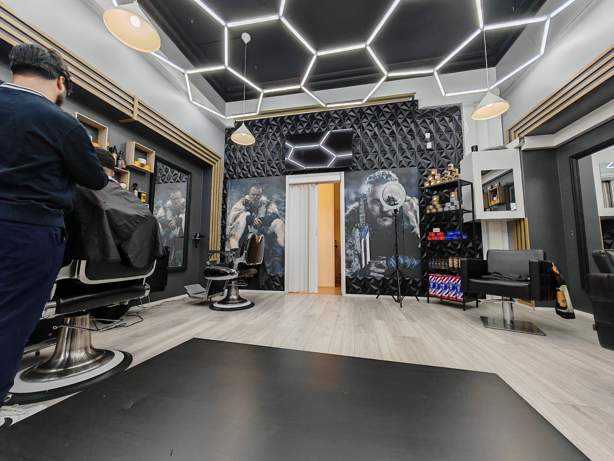 A barber carefully cuts a seated customer's hair.